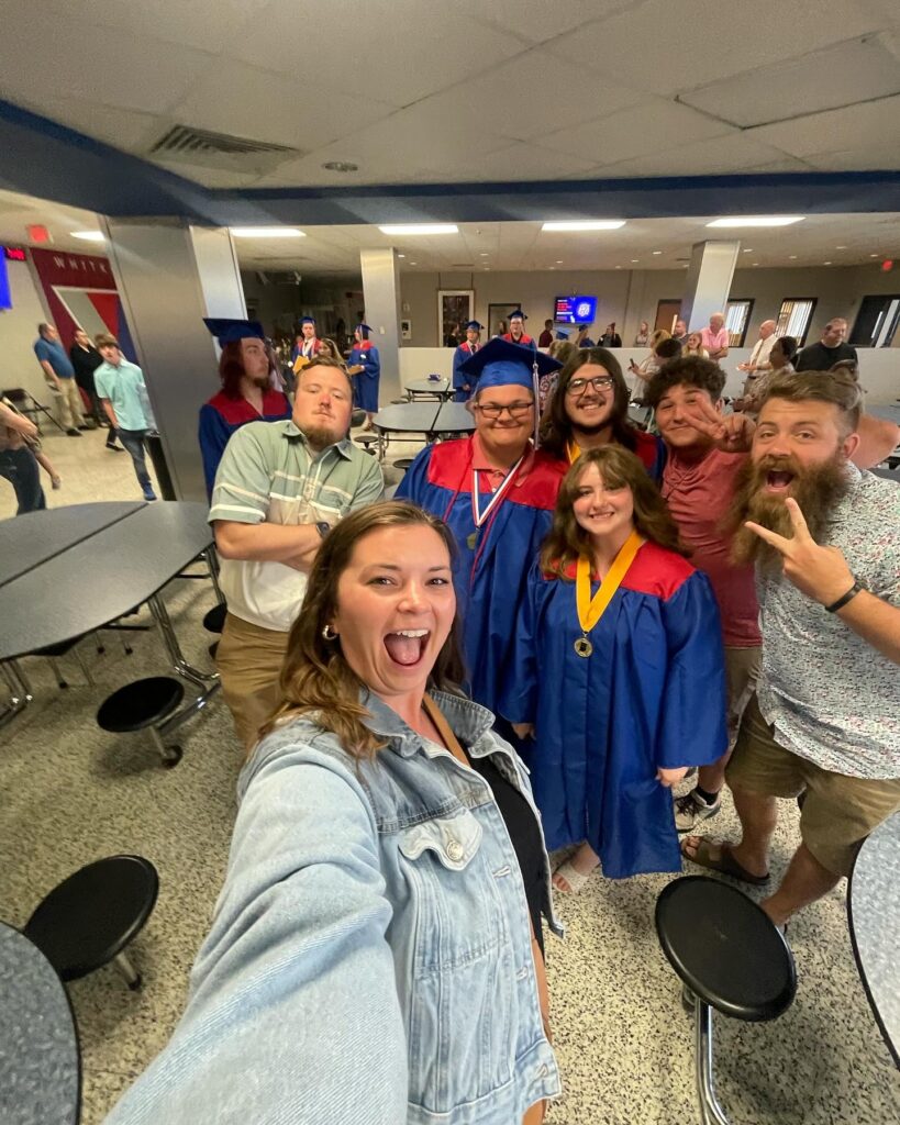 A student taking a selfie with a group of graduates in caps and gowns