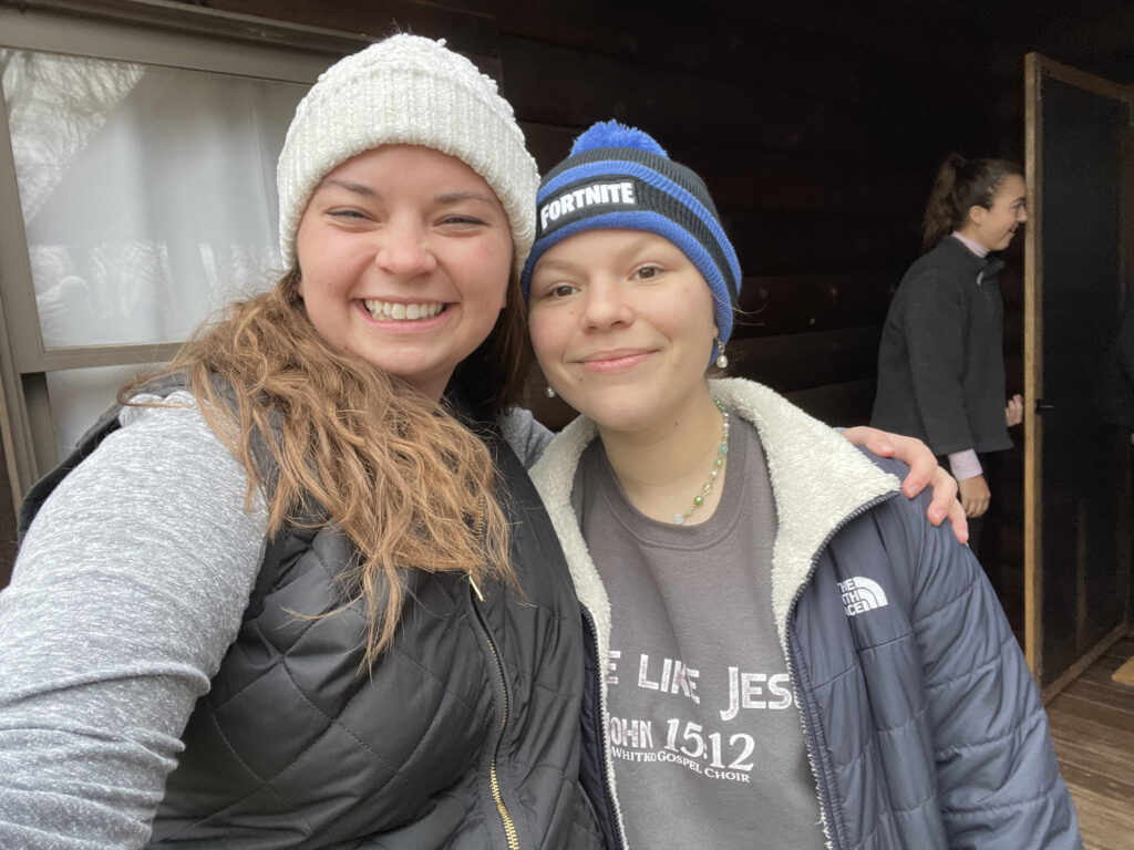 Two students in winter hats smiling for a photo