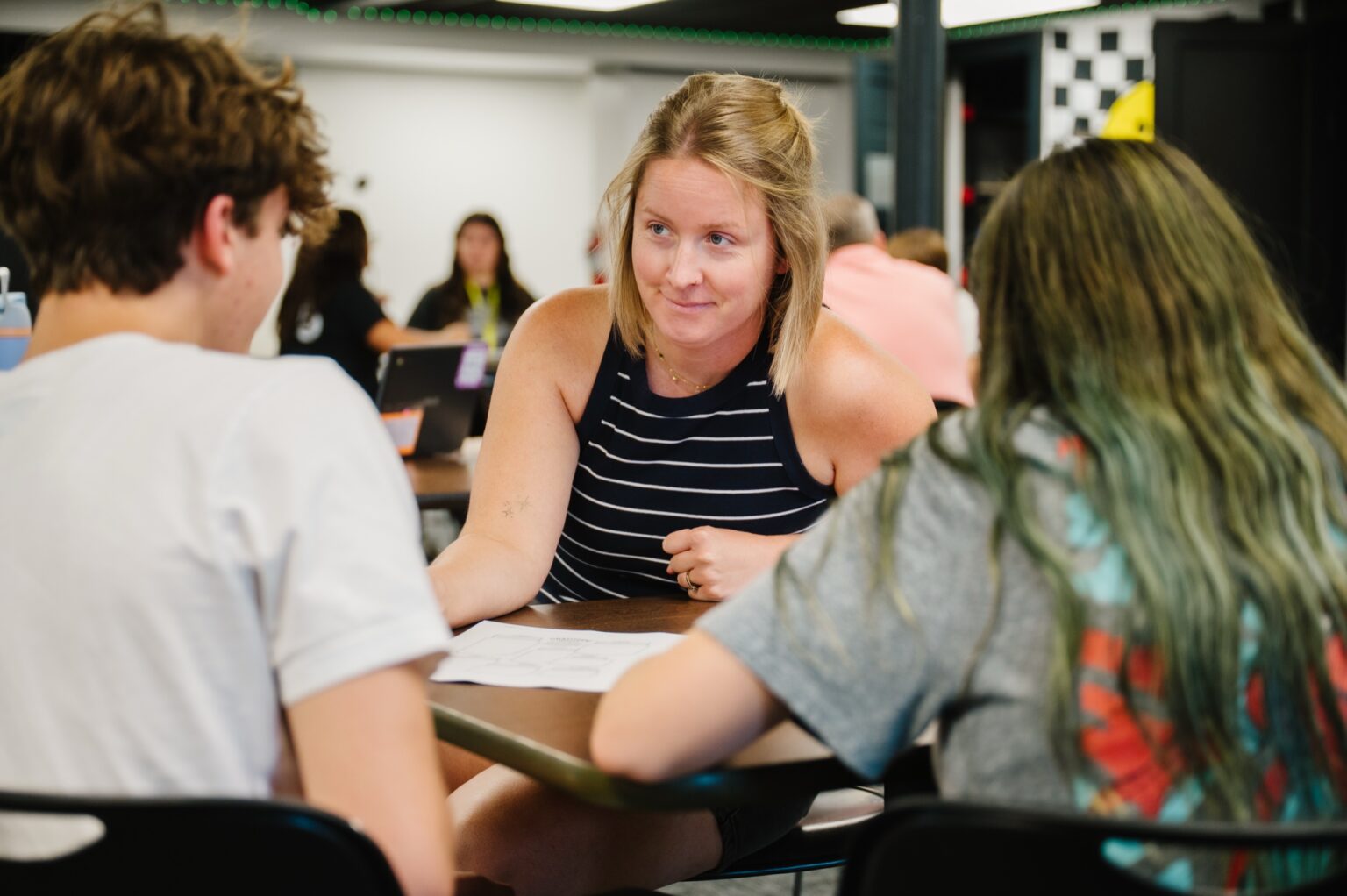 A volunteer working with a group of students at a table at The Center